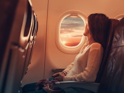 Una mujer mira por la ventana de una avión.