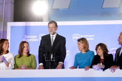 Mariano Rajoy saluda a cientos de simpatizantes del PP desde el balcón de la sede nacional del partido flanqueado, de izquierda a derecha, por Ana Mato; Elvira Fernández, esposa del líder popular; Dolores de Cospedal y Soraya Sáenz de Santamaría.