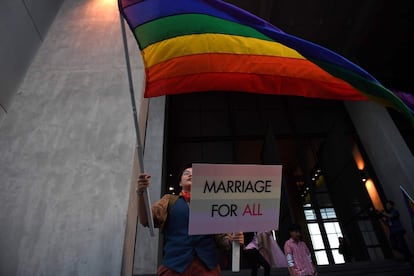 Un manifestante ondea una bandera mientras sostiene una pancarta en la que se puede leer "Matrimonio para todos", durante una protesta en defensa de los derechos de los homosexuales en Bangkok (Tailandia).