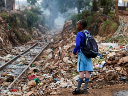 Una estudiante junto a la línea ferroviaria Kenia-Uganda a su paso por Nairobi ataviada con el uniforme del colegio.
