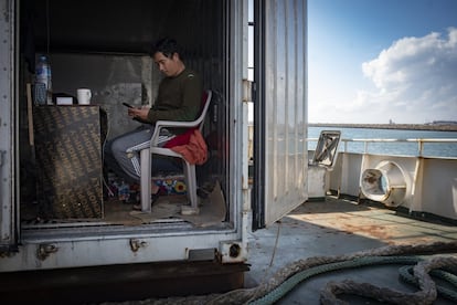 El mecánico Than Htike mira su teléfono en el contenedor donde duerme, en la popa del buque 'Sea Condor'.