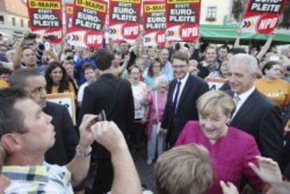 La canciller alemana Angela Merkel (2&ordm;dcha)saluda a sus simpatizantes junto al presidente de Sajonia, Stanislaw Tillich (dcha), durante una campa&ntilde;a electoral en Oschatz (Alemania).