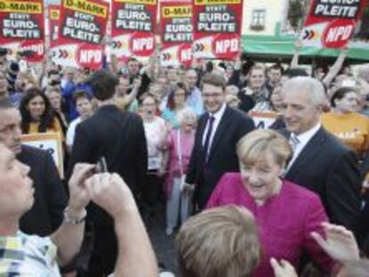 La canciller alemana Angela Merkel (2&ordm;dcha)saluda a sus simpatizantes junto al presidente de Sajonia, Stanislaw Tillich (dcha), durante una campa&ntilde;a electoral en Oschatz (Alemania).