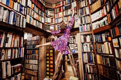 A woman looking for a book in a bookshelf.