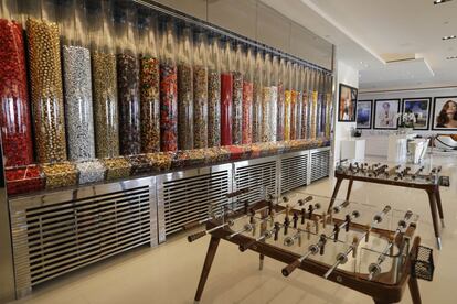 Una pared repleta de dispensadores de caramelos en el salón de la mansión, al lado de dos futbolines. 