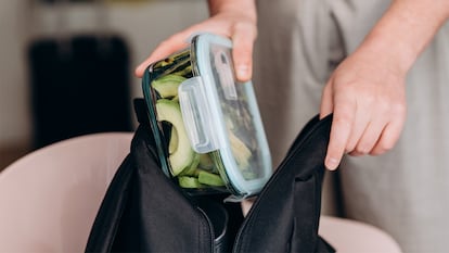 Una chica metiendo el tapper en la bolsa de comida para el trabajo.