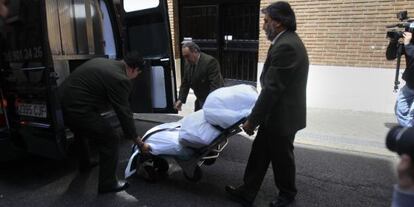 Empleados de la funeraria trasladan el cuerpo de la mujer.