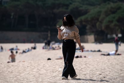 Una mujer pasea mientras consulta su teléfono móvil por la playa de Castell-Platja D'Aro, cerca de Girona, este miércoles.