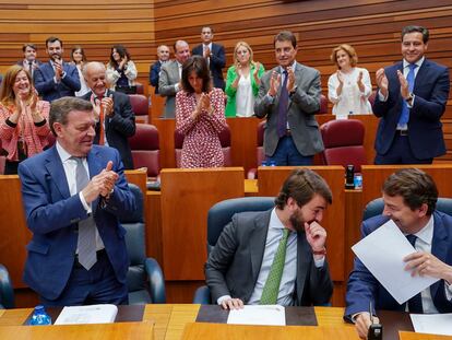 El presidente de la Junta de Castilla y León, Alfonso Fernández Mañueco (a la derecha), ríe mientras conversa con el vicepresidente, Juan García Gallardo (a la izquierda de Mañueco), mientras recibe los aplausos de los miembros de la bancada popular, en las Cortes, en Valladolid, este martes.