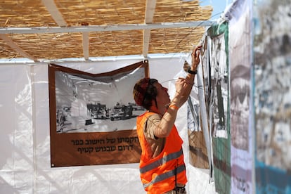 A settler places posters on the wall of one of the camp's tents on Monday.