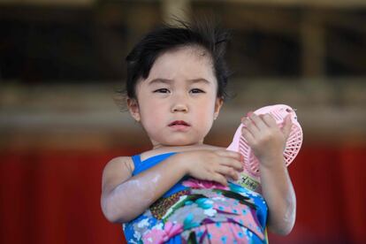 Una niña sostiene un pequeño ventilador disfrazada de la ex legisladora Emily Lau.