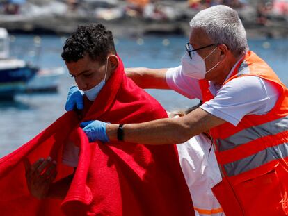 A member of the Red Cross assists a migrant after disembarking from a Spanish coast guard vessel, at the port of Arguineguin