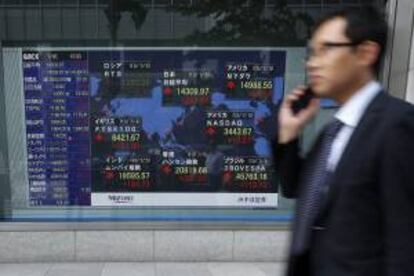 Un hombre pasa delante de una pantalla que muestra varios valores bursátiles en Tokio. EFE/Archivo
