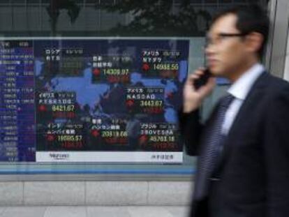 Un hombre pasa delante de una pantalla que muestra varios valores bursátiles en Tokio. EFE/Archivo