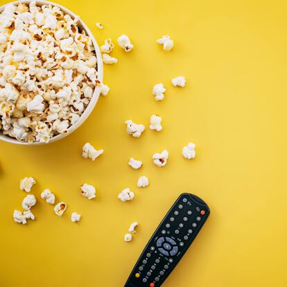 Popcorn and TV Remote Controller On Yellow Background