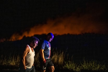 Dos vecinos, en la noche de este sábado con las llamas al fondo del incendio de Vilardevós (Ourense).

