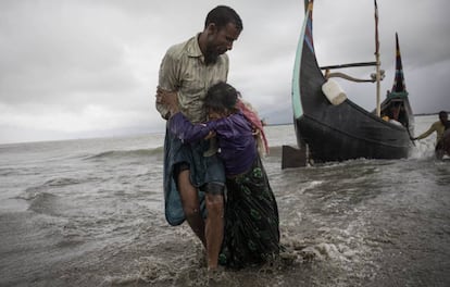 IMÁGENES DEL DÍA: Un refugiado de la etnia Rohingya ayuda a una mujer anciana tras bajar del barco en el que viajaban desde Myanmar, en Dakhinpara (Bangladés).