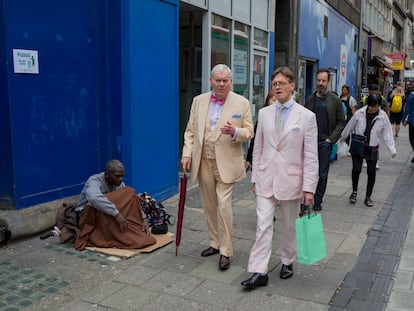 Un sintecho y dos hombres bien vestidos en la calle Oxford, en Londres.