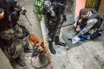 La policía militar incauta una mochila con las drogas y municiones con la ayuda de un perro rastreador en el Complexo da Maré, en Río de Janeiro.