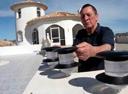 Tom, uno de los afectados, carga lámparas solares por la falta de electricidad en su vivienda.