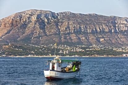 Un barco en la bahía de Dénia y, al fondo, el macizo de Montgó.