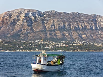 Un barco en la bahía de Dénia y, al fondo, el macizo de Montgó.