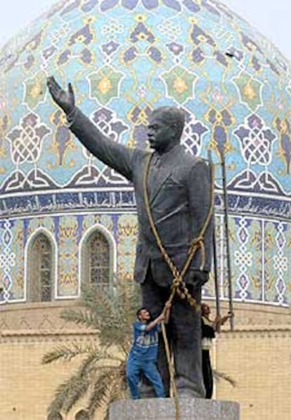 Dos bagdadíes encaramados a una estatua de Sadam, a la que han colocado una cuerda para derribarla.
