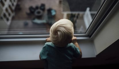 Un bebé mira por una ventana.