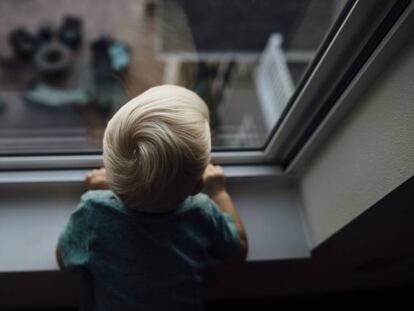 Un bebé mira por una ventana.