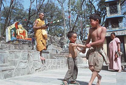 Dos niños juegan en un templo de Tíbet en presencia de un monje.