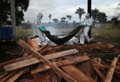 Un equipo de enterradores contratados por el Ministerio de Sanidad de Liberia traslada cuerpos de víctimas del ébola a una pira funeraria en la localidad de Marshall, en agosto de 2014.