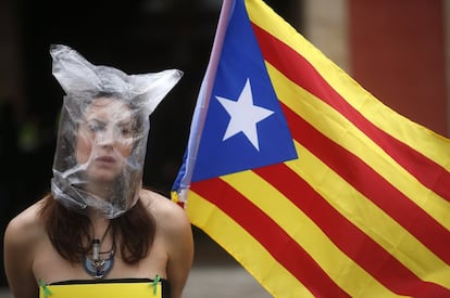 Una participante en la concentración por la independencia de Cataluña con la cabeza cubierta con una bolsa de plástico y sujetando una bandera catalana frente al Parlamento catalán.