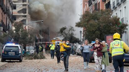 Lola López-Bravo (con botas de agua) se aleja del lugar de la explosión mientras un bombero de paisano lleva en brazos a su hijo Matías.