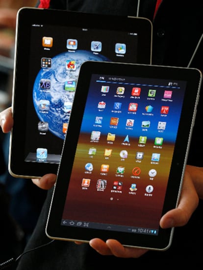 Un empleado surcoreano de la telefónica KT sostiene una tableta Samsung Galaxy junto a un iPad de Apple.