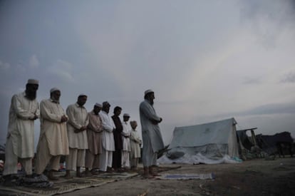 Un grupo de musulmanes paquistaníes, supervivientes de las fuertes inundaciones, reza en una carretera de Charsadda, donde permanecen tras la perdida de sus hogares.