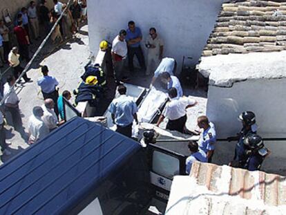 Trabajadores de los servicios funerarios sacan de la casa los cuerpos de las víctimas del incendio.