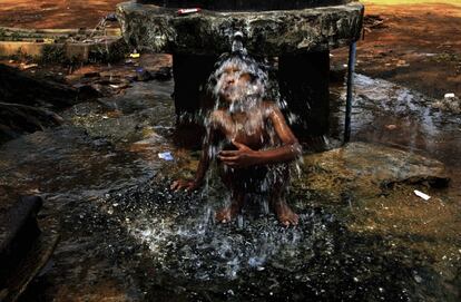 Un niño se moja en una fuente de un baño público en la ciudad india de Bhubaneswar (India).