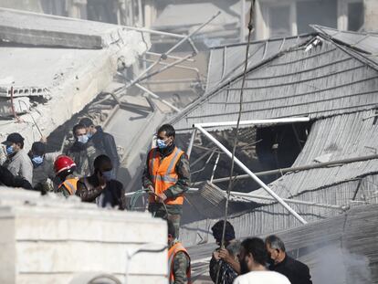 Trabajadores de emergencias y ciudadanos congregados ante el edificio destruido en Damasco en un ataque aéreo este sábado.
