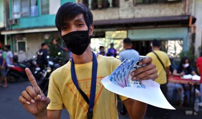 Un joven muestra el sobre con dinero que acaba de recibir como parte de la ayuda asignada por el Gobierno a los sectores más pobres.