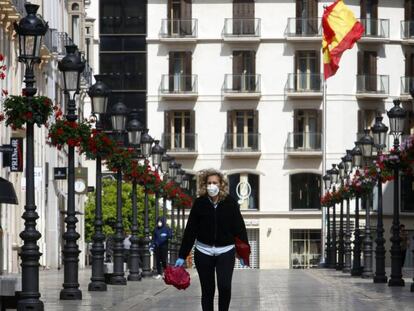 Una mujer con mascarilla recorre la calle Larios de Málaga.
 
 