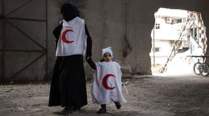 Una mujer siria y un niño esperan a ser evacuados por la Media Luna Roja Árabe Siria de una zona controlada por los rebeldes.
