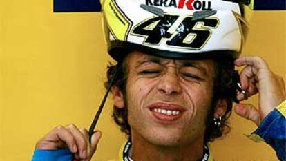 Valentino Rossi se coloca el casco con gesto dolorido por las lesiones que sufre en su mano izquierda.