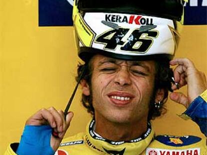 Valentino Rossi se coloca el casco con gesto dolorido por las lesiones que sufre en su mano izquierda.