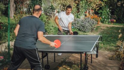 Dos hombres en un jardín jugando al ping pong.