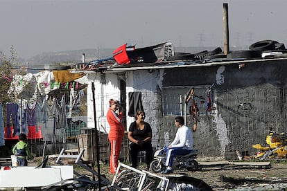 Una familia, frente a una de las chabolas existentes en el distrito de Villaverde.