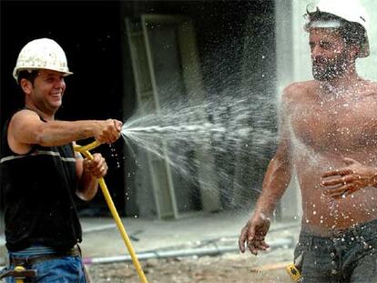 Dos obreros de la construcción se refrescan para combatir el calor.