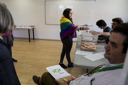 Una mujer ataviada con la bandera LGTBI vota en un colegio electoral de Madrid.