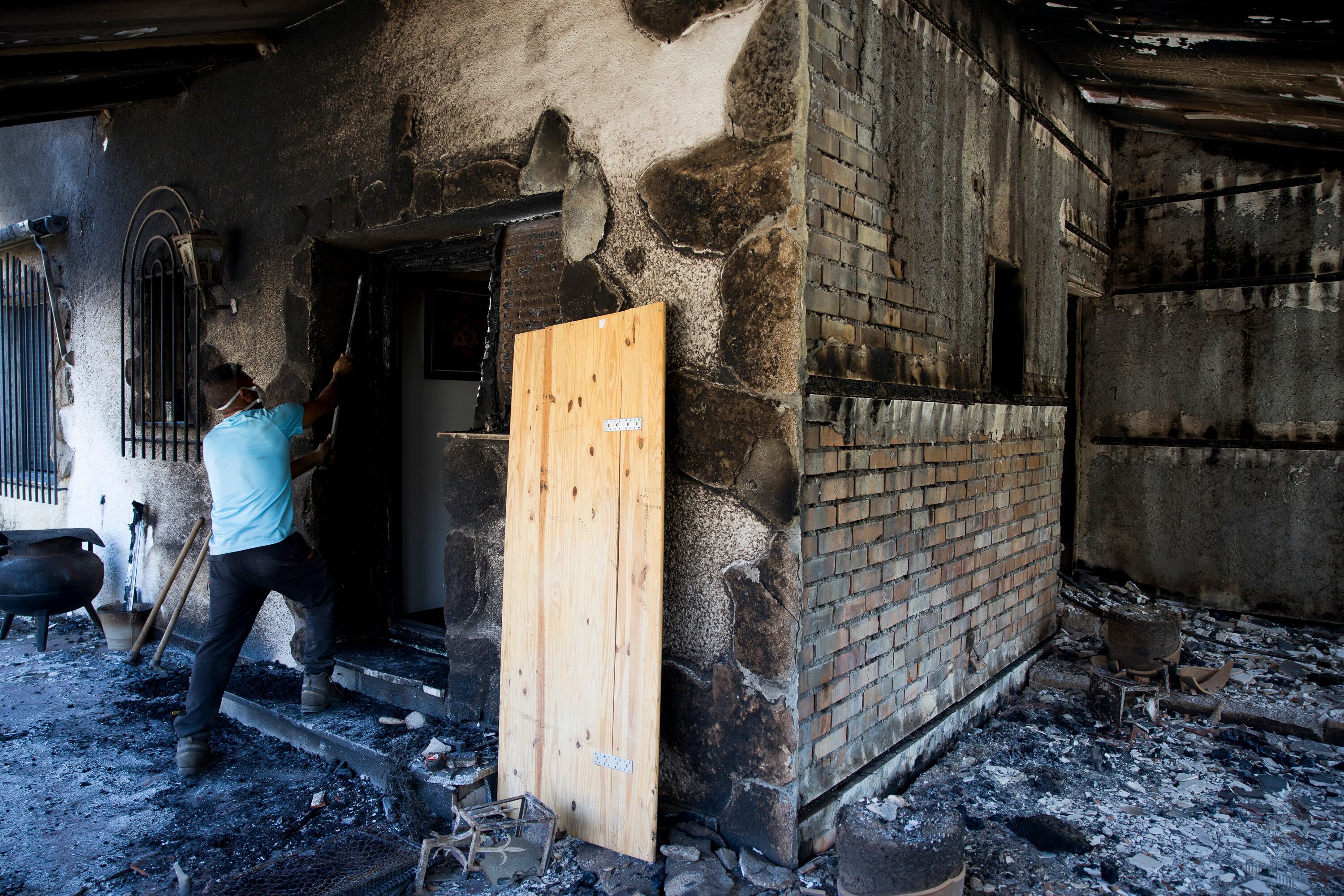 El técnico de mantenimiento de la urbanización Calas de Burguillo en Navaluenga comprueba los desperfecto de la vivienda tras el incendio forestal, este domingo. 