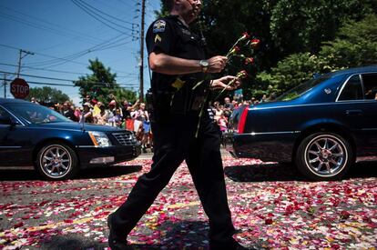 Un oficial de policía lleva flores durante el cortejo fúnebre.