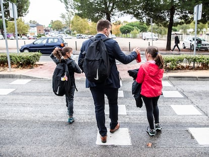 Un padre acompaña a sus hijas al colegio en municipio de la Comunidad de Madrid. CARLOS ROSILLO.